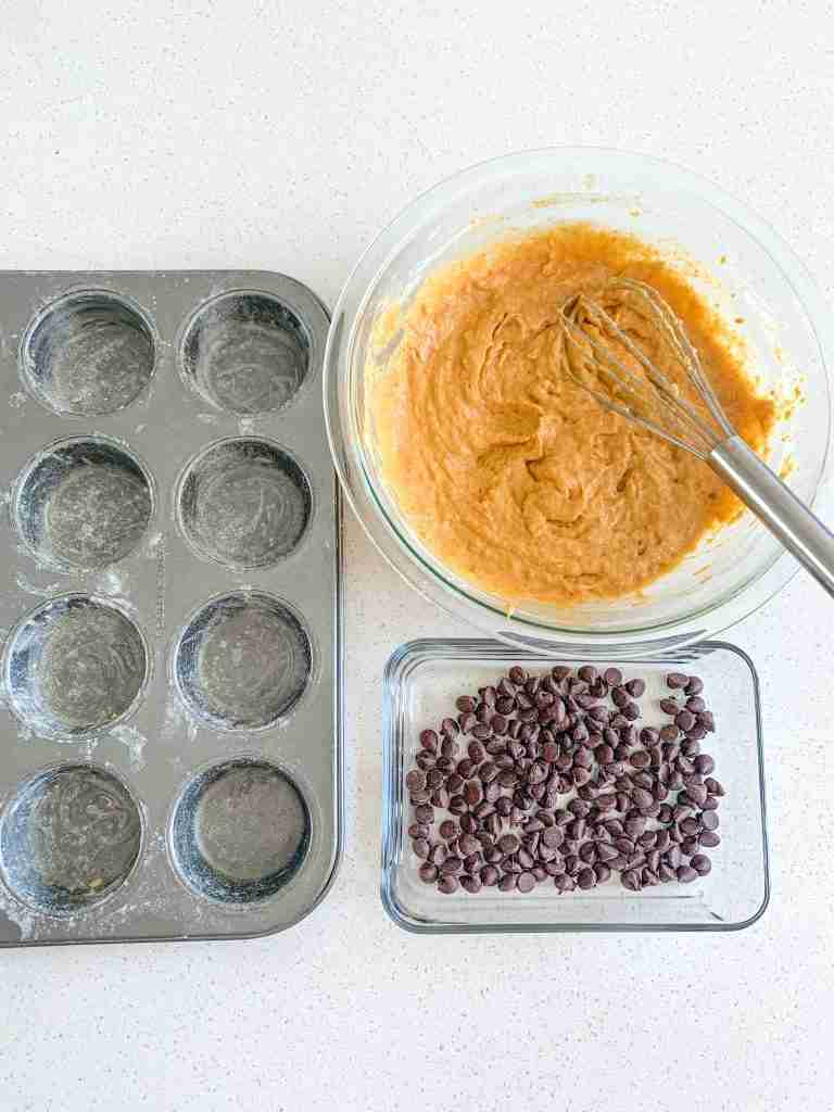 prepared muffin tray, sourdough pumpkin muffin batter, and chocolate chips