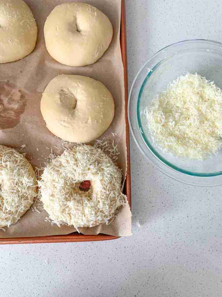 topping boiled bagels with shredded asiago cheese before baking