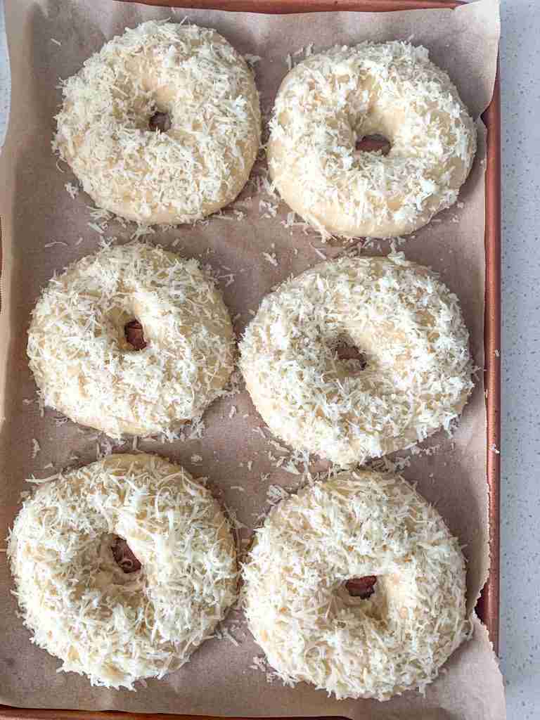 boiled bagels covered in asiago cheese ready to be baked