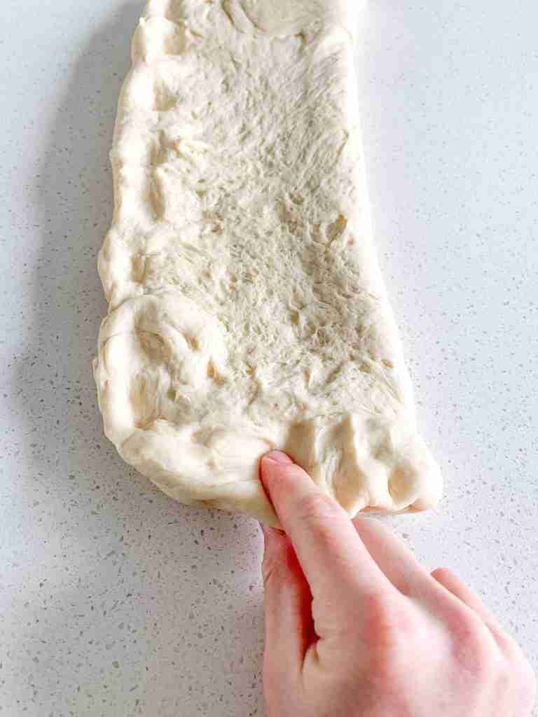 pinching steakhouse roll dough together to seal the edges