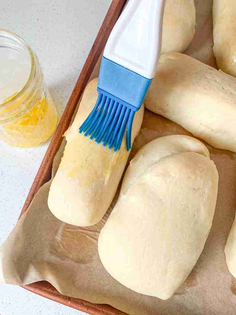 brushing baked rolls with butter