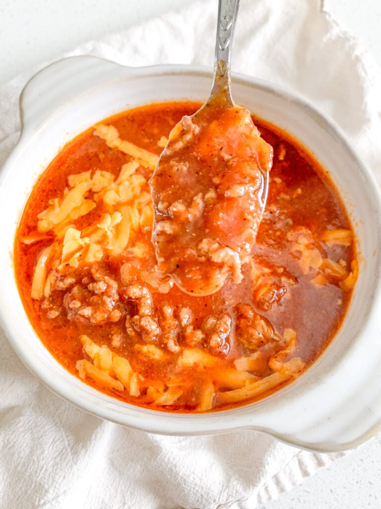 freshly made bowl of game day chili topped with cheese being enjoyed