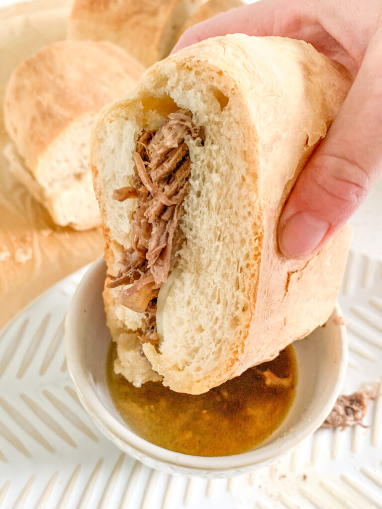 french dip sandwich getting dipped in au jus