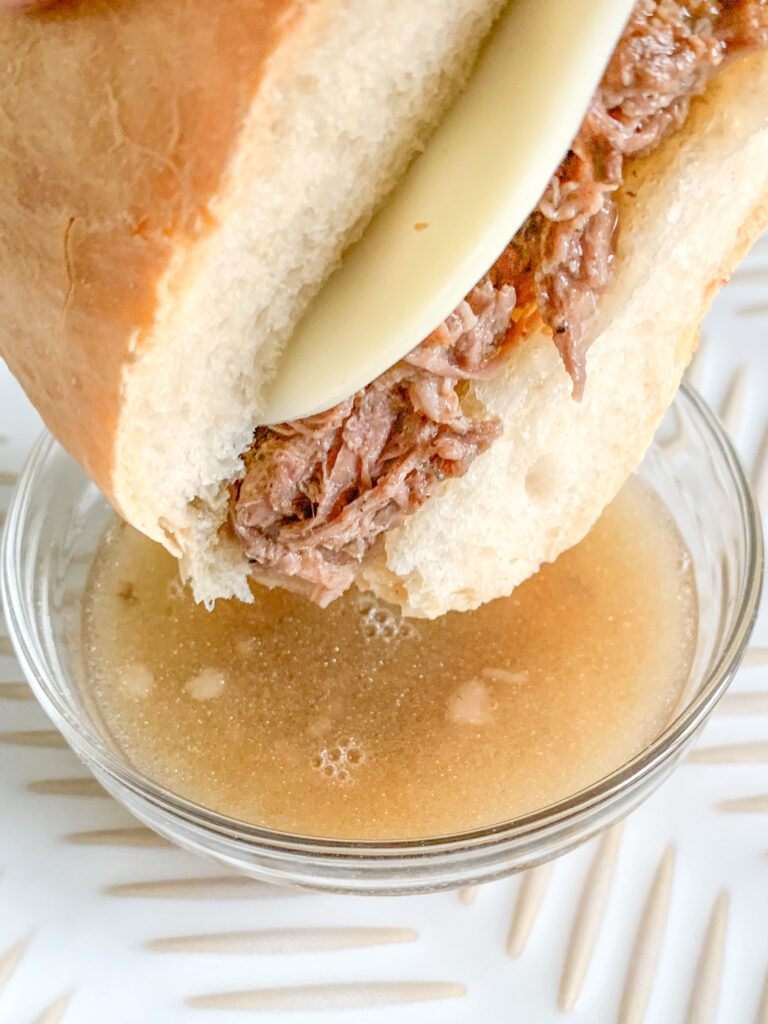 french dip sandwich getting dipped in au jus