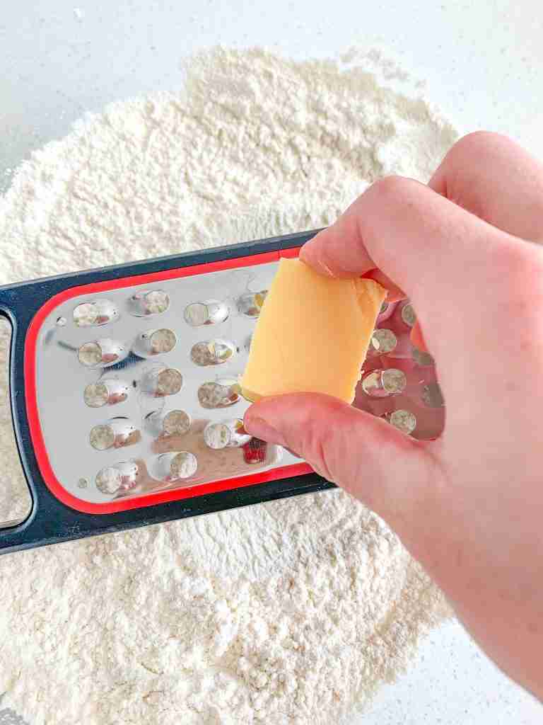 using a cheese grater to grate butter into dry biscuit ingredients