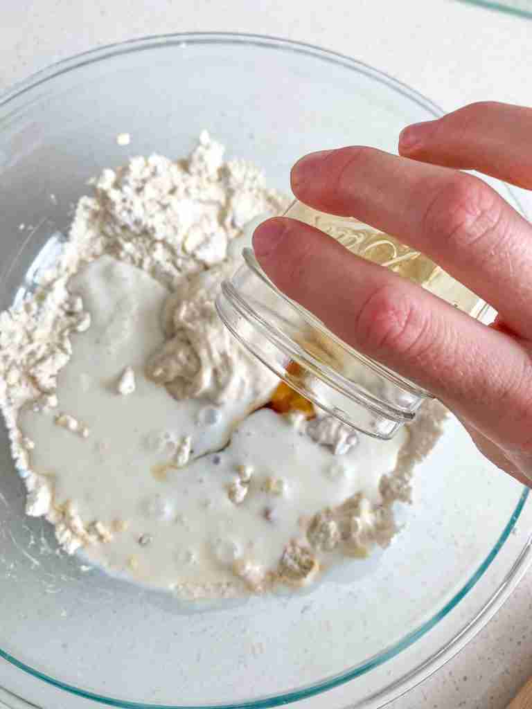 pouring wet ingredients into dry to make maple bacon biscuits