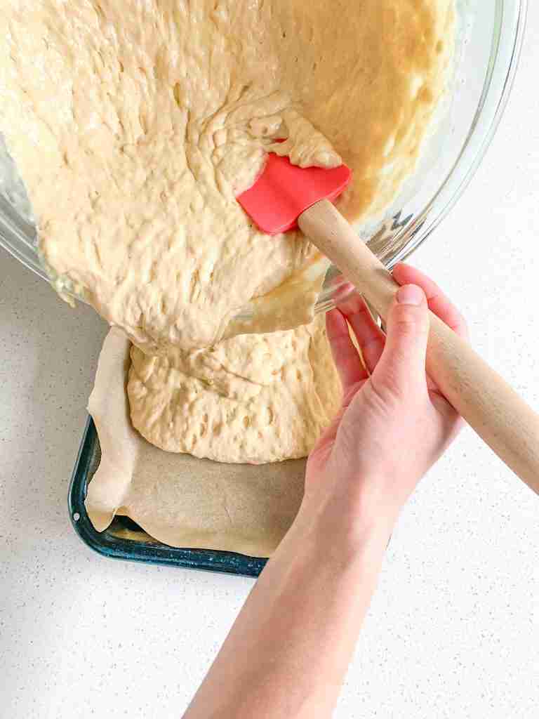 adding the first layer of sourdough coffee cake batter to the pan