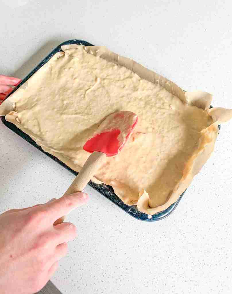 smoothing out the second layer of sourdough coffee cake batter in the pan