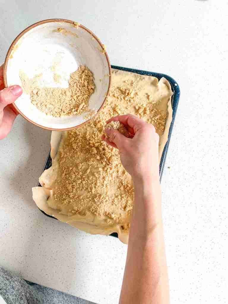 adding streusel topping to sourdough coffee cake batter before baking