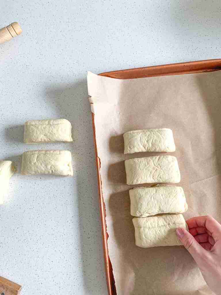 lining shaped sourdough parker house roll dough on a baking sheet