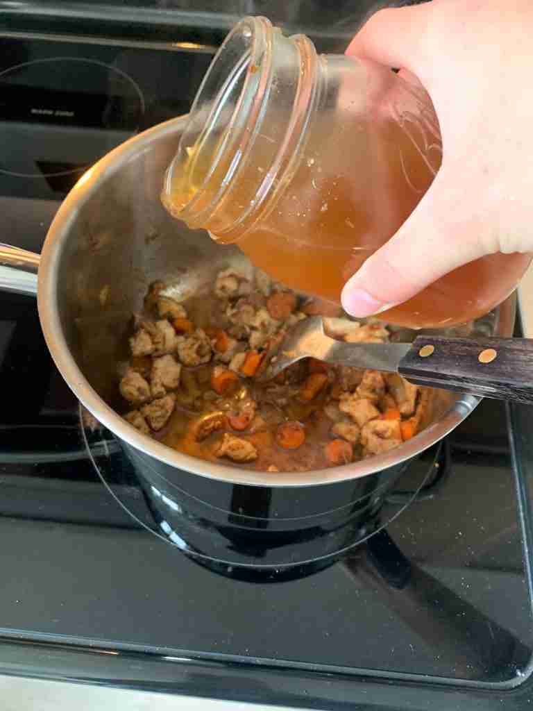 pouring chicken broth into the pan to make chicken gnocchi soup
