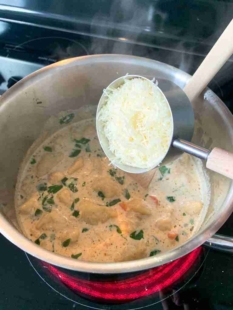 adding parmesan to the pot to make chicken gnocchi soup