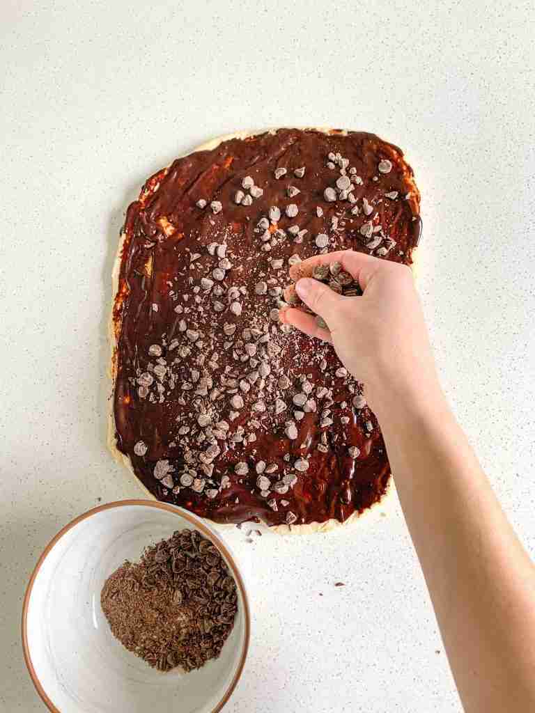 sprinkling chocolate chips over sourdough babka dough