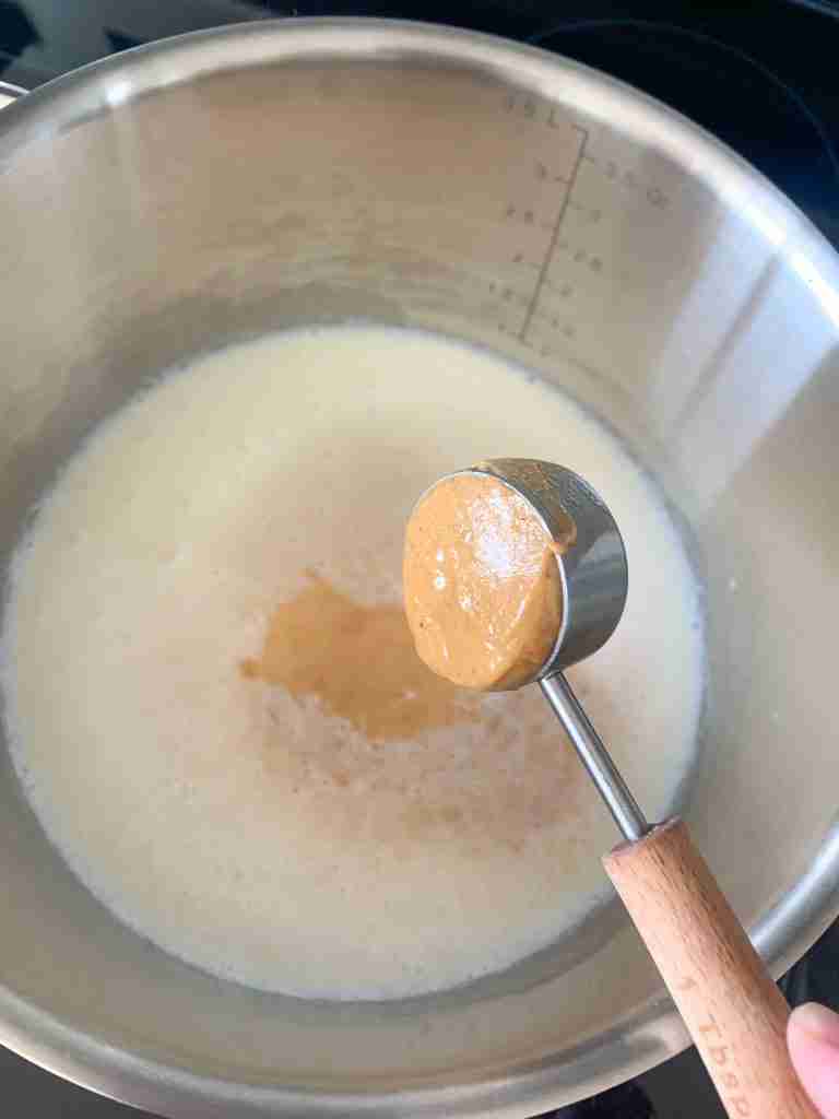peanut butter being added to milk for peanut butter hot chocolate