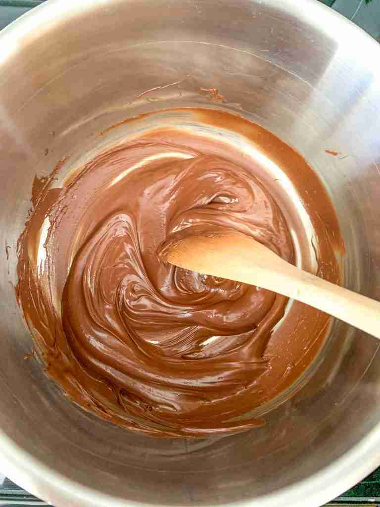 chocolate being melted in a pan for coating homemade little debbie cakes