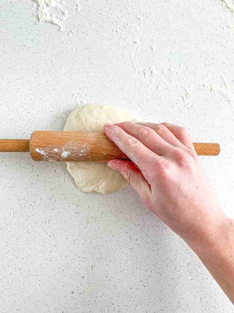 hand rolling out calzone dough