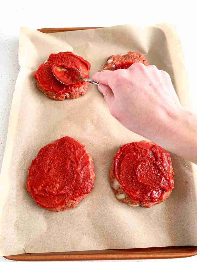 spreading ketchup sauce on meatloaf patties