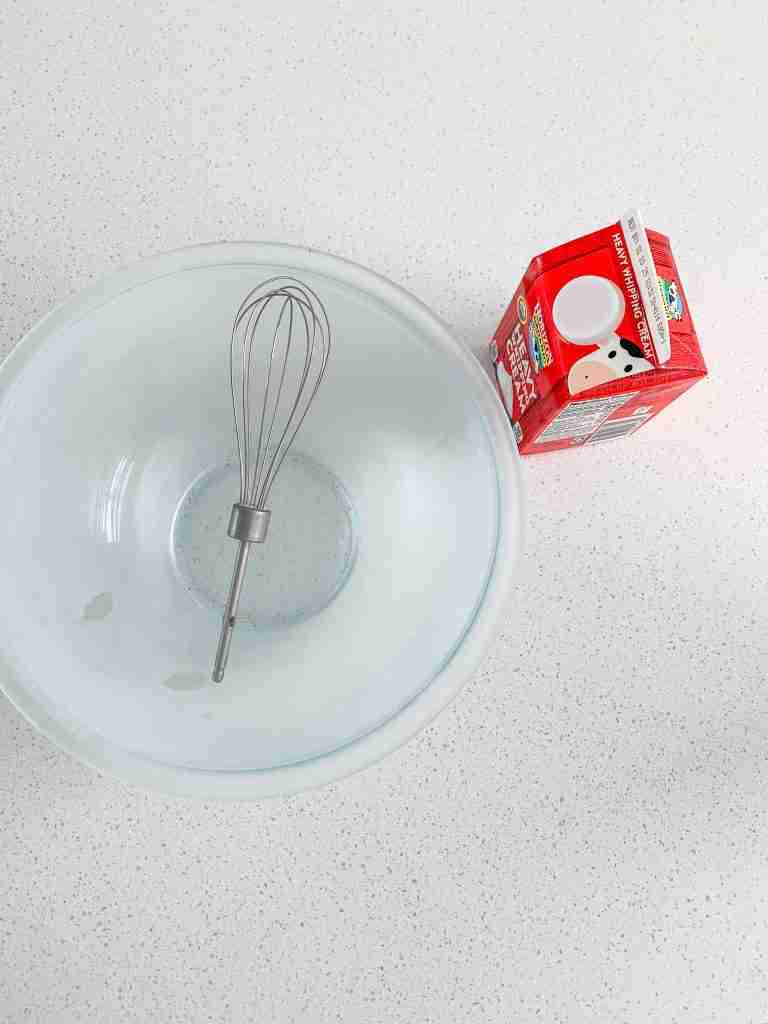 cold bowl and heavy whipping cream ready to be used for stabilized whipped cream frosting