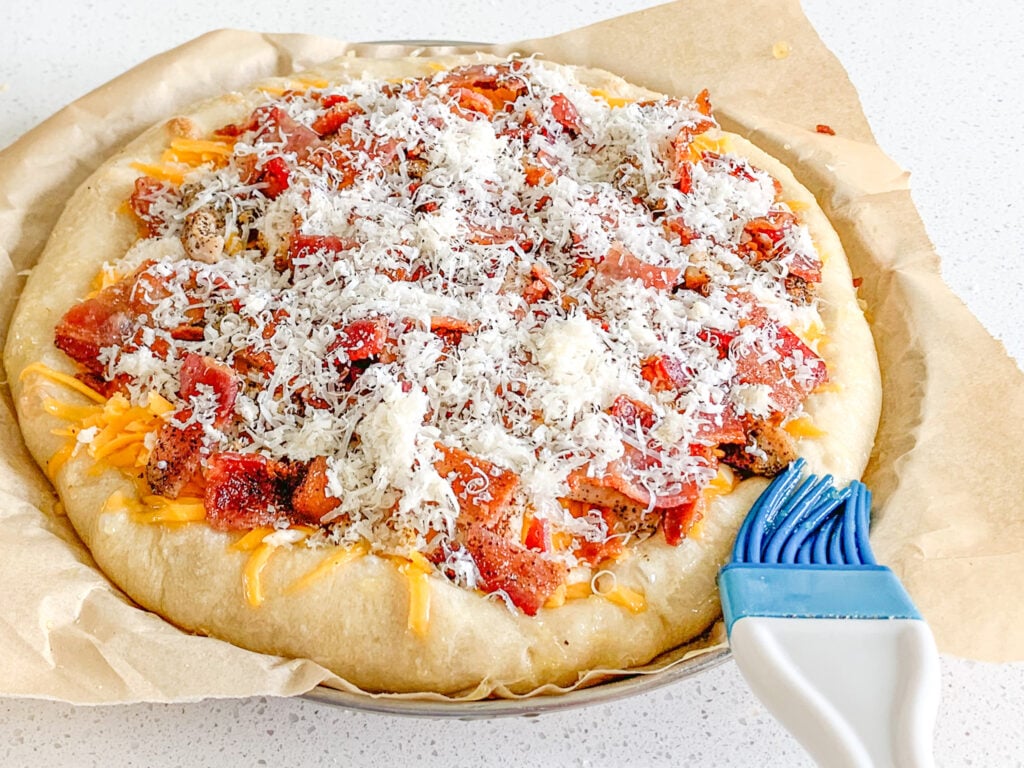 brushing pizza crust with garlic oil