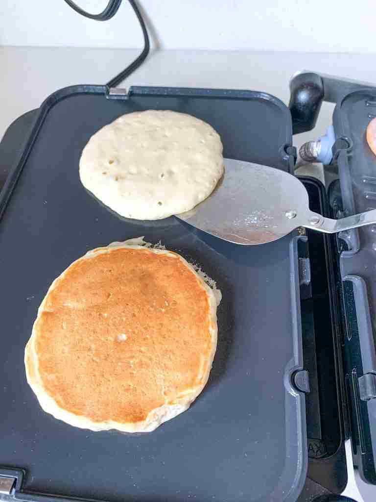 flipping sourdough buttermilk pancakes on a griddle while cooking