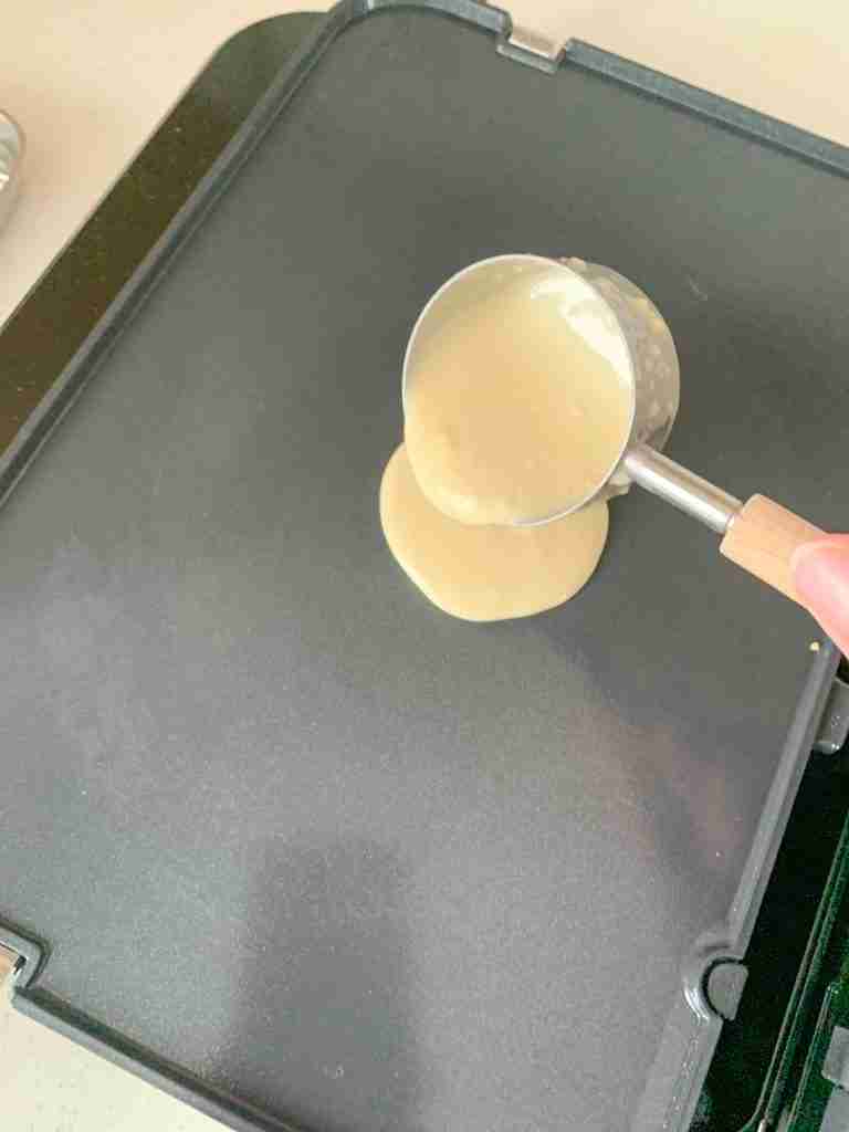 pouring sourdough crepe batter on a griddle