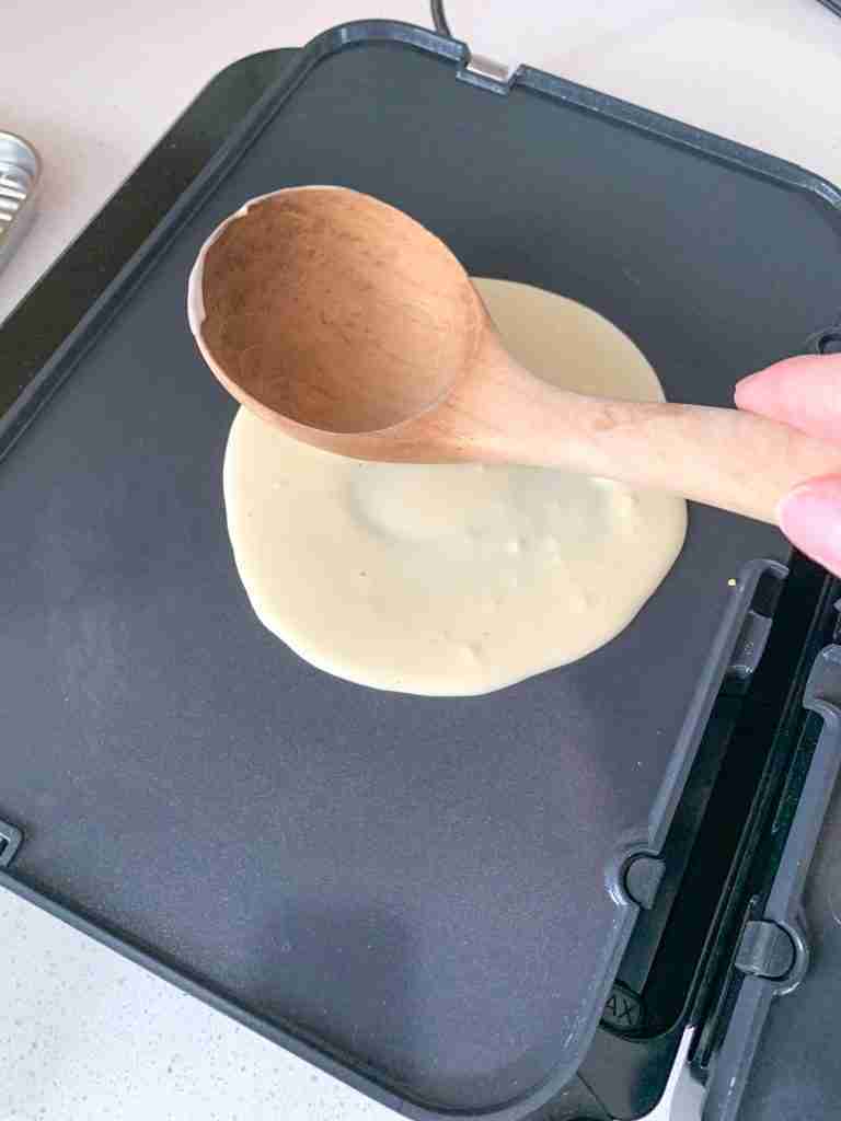 smoothing sourdough crepe batter out on a griddle