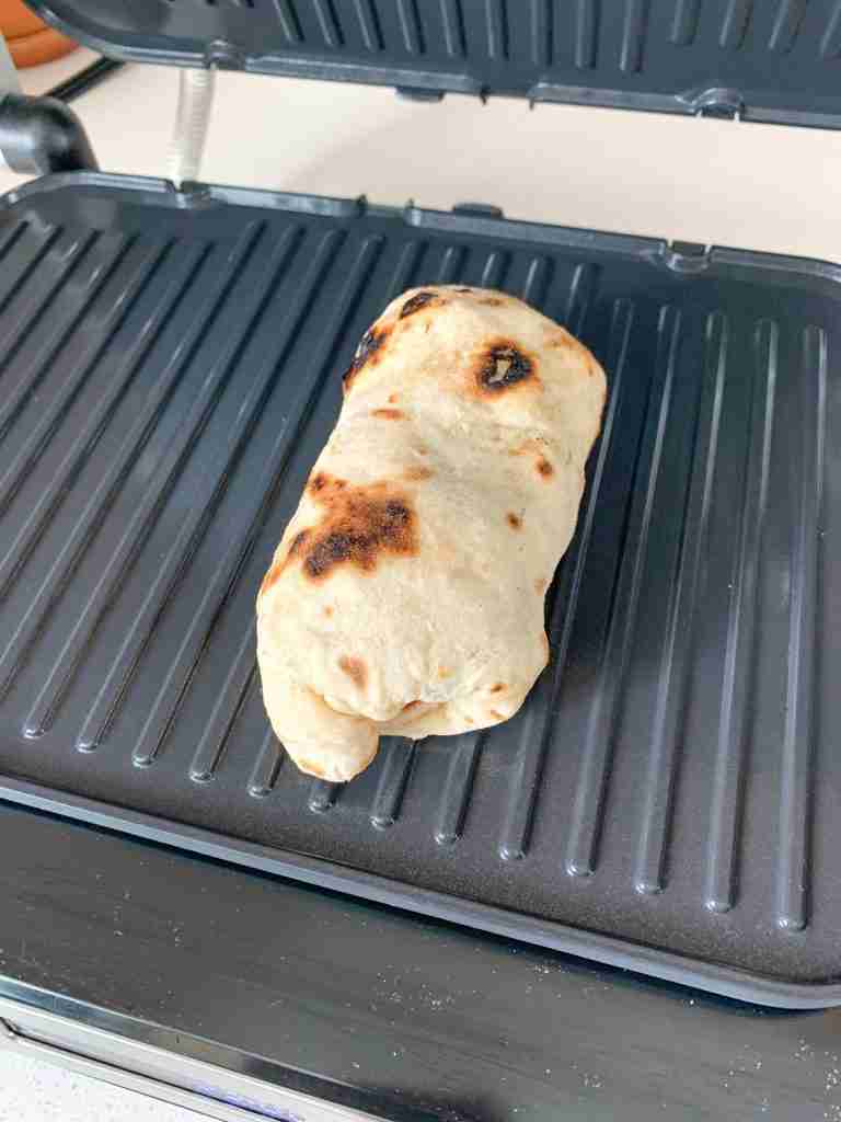 assembled bacon breakfast burrito on a griddle searing the shell