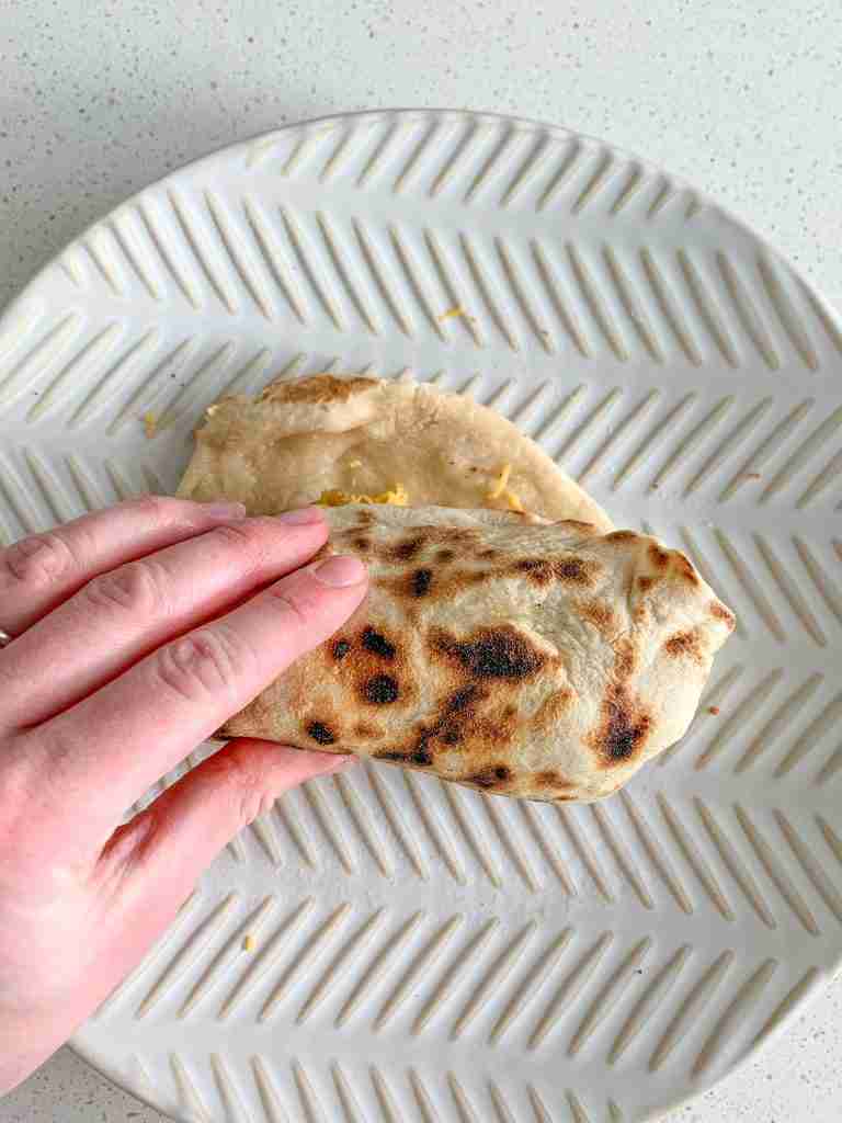 rolling the filled tortilla for bacon breakfast burrito