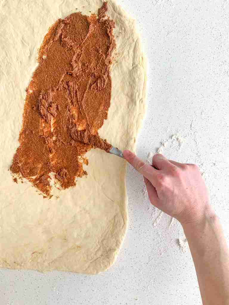filling being spread on sourdough maple cinnamon roll dough