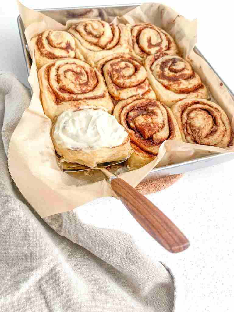 frosted freshly baked maple cinnamon rolls getting served