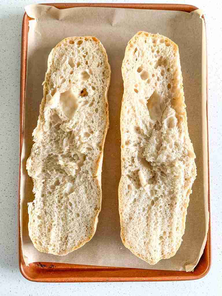 French bread sliced in half for sourdough pesto garlic bread