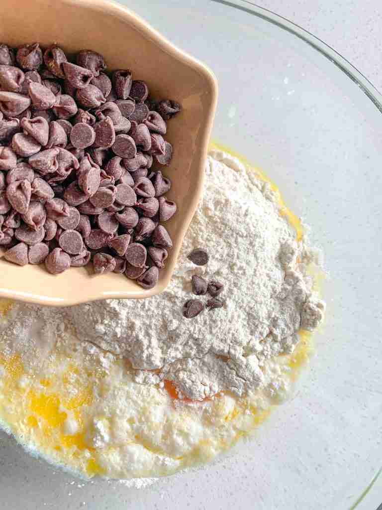 adding ingredients into a bowl for sourdough chocolate chip muffins
