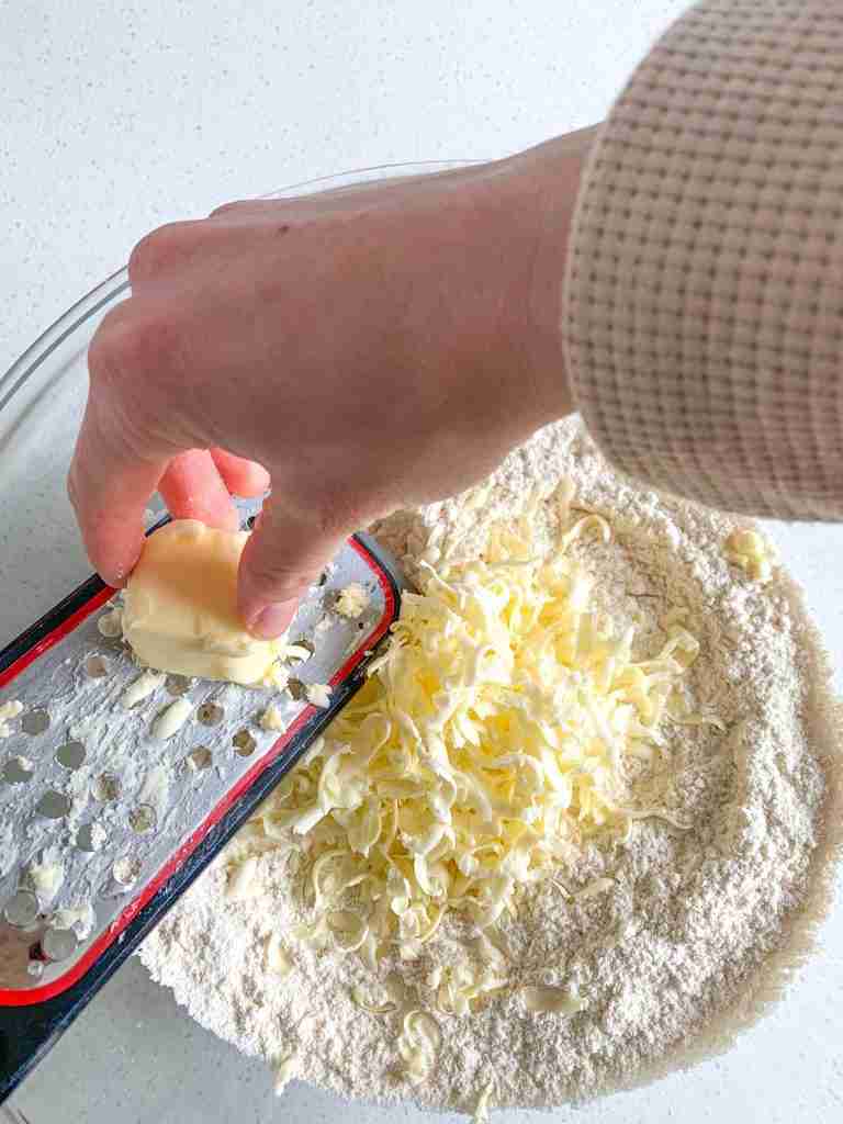 butter being grated into a flour mixture for sourdough orange scones
