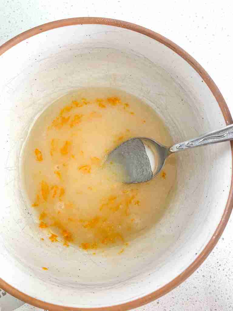 bowl of orange glaze ready for drizzling on sourdough orange scones