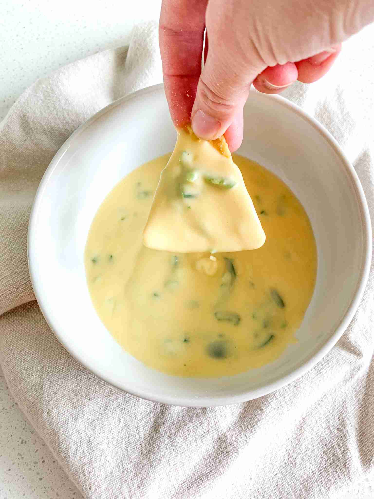 a tortilla chip dipped in cheese dip