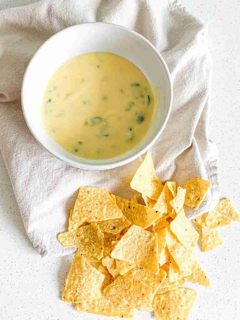 bowl of jalapeno cheese dip and tortilla chips beside it