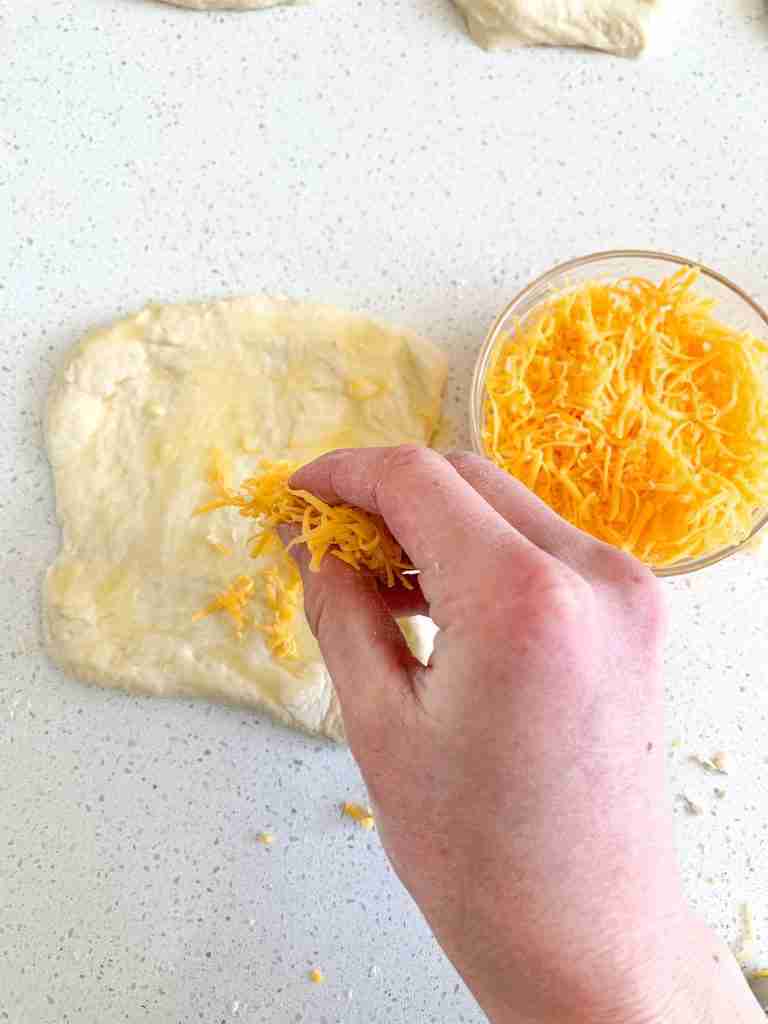 adding cheddar to sourdough garlic pull apart bread dough