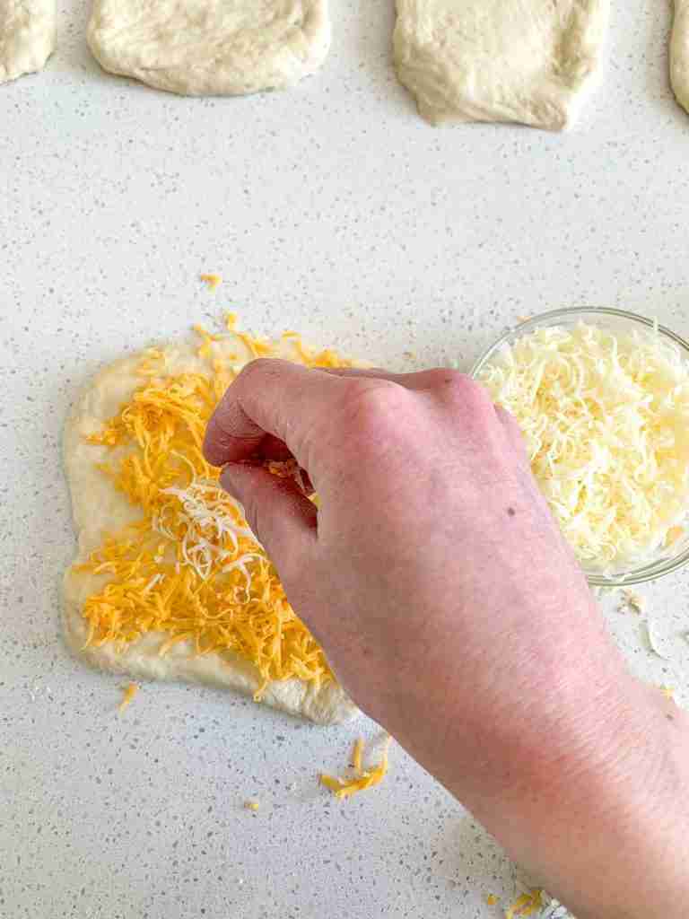 adding cheese to slices of sourdough garlic pull apart bread