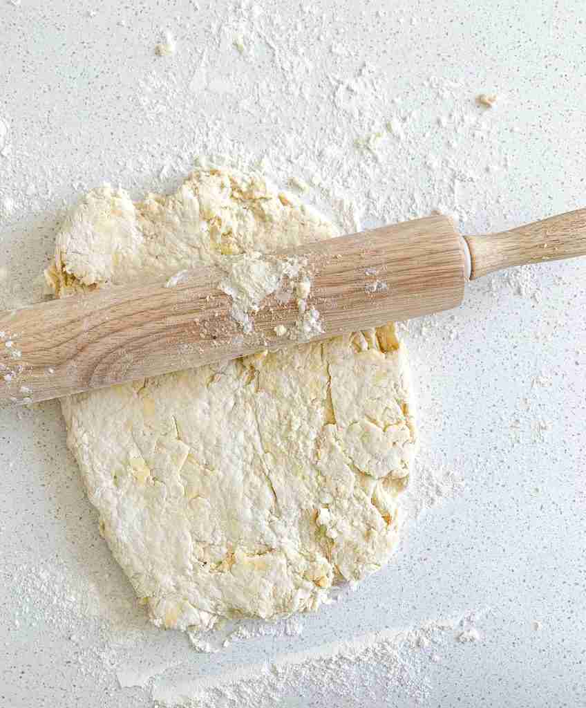 rolling out biscuit dough for sourdough breakfast sandwiches