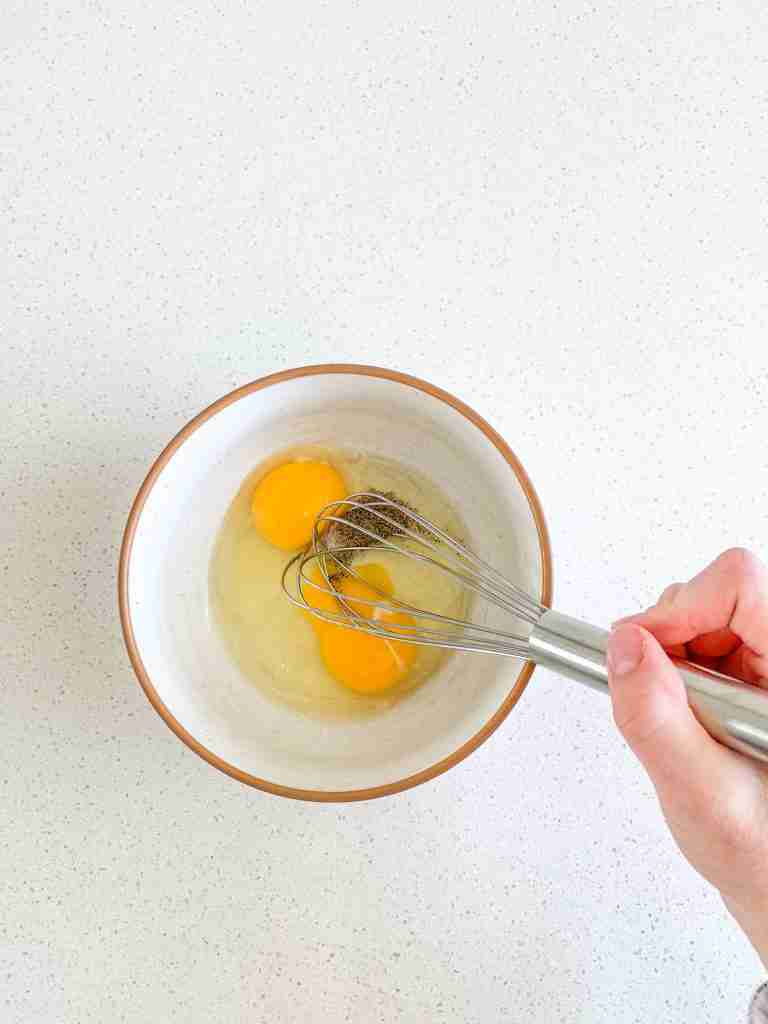 whisking eggs and seasoning for sourdough breakfast sandwiches