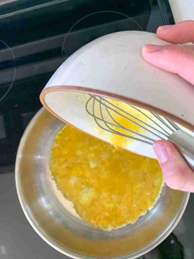 adding eggs to skillet for sourdough breakfast sandwiches