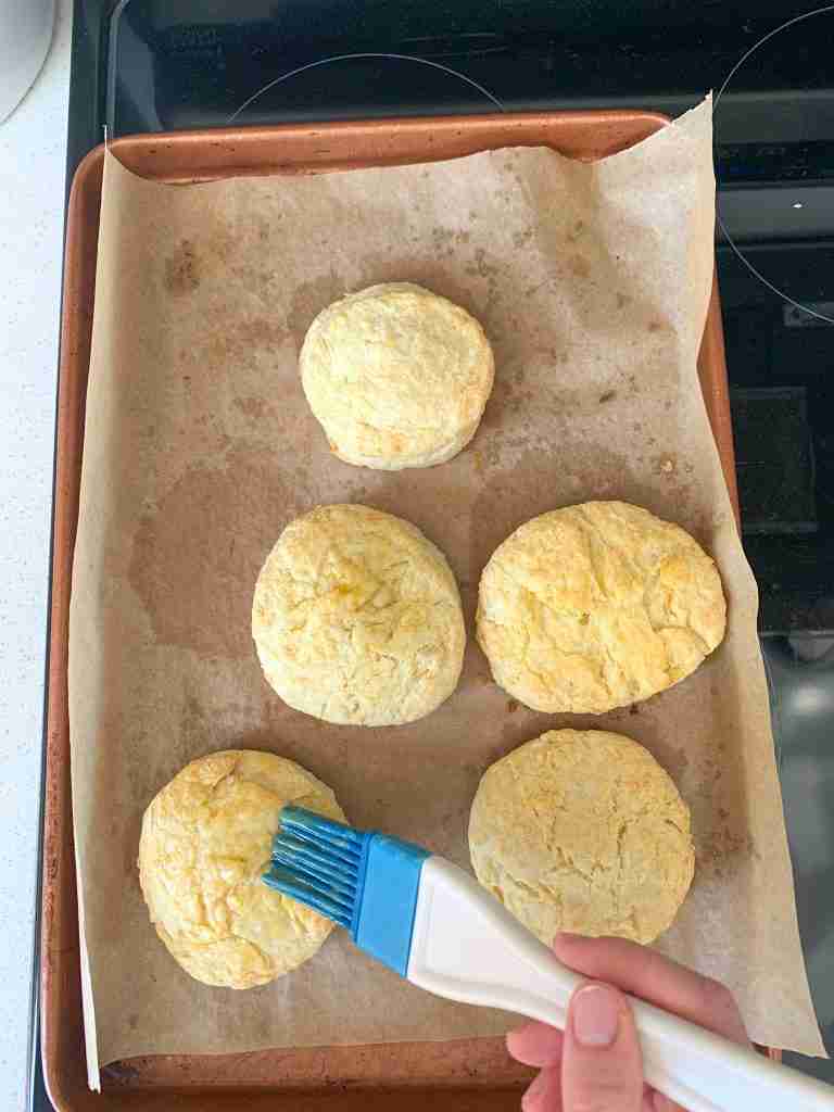 brushing butter on biscuits for sourdough breakfast sandwiches