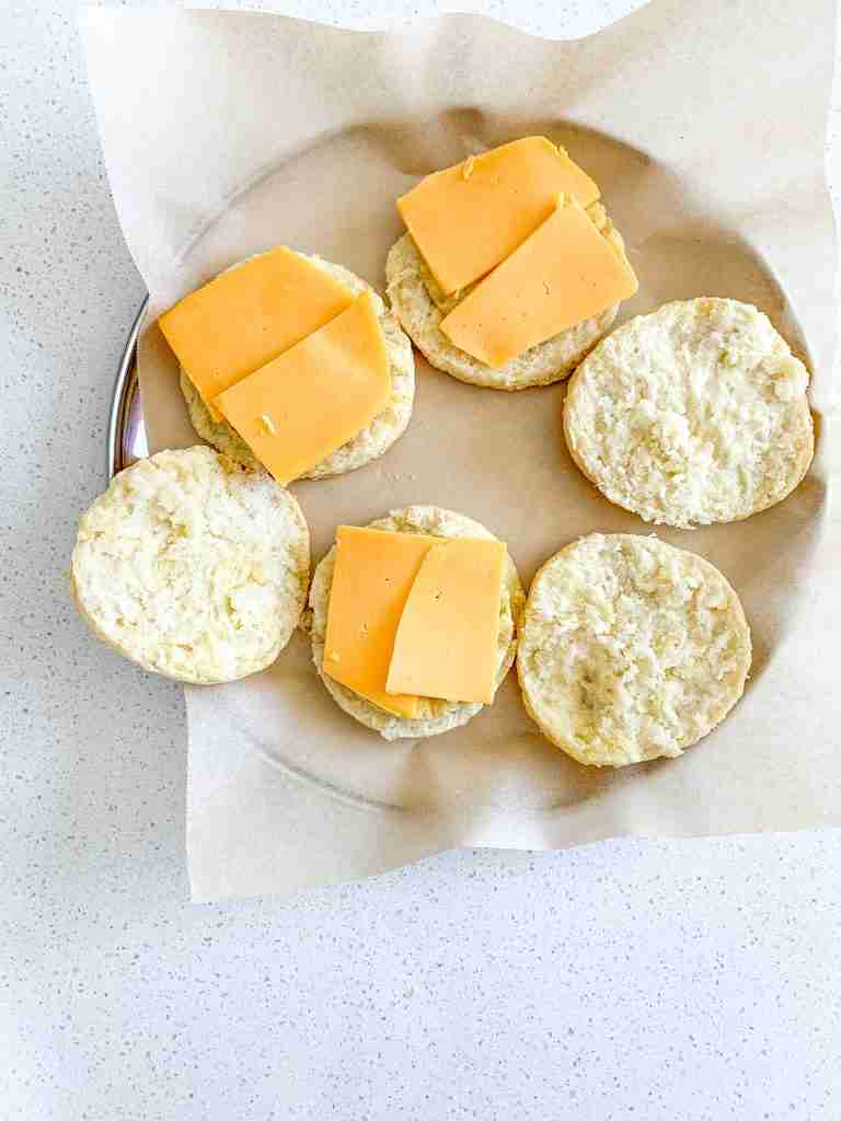 cheese on biscuits while assembling sourdough breakfast sandwiches
