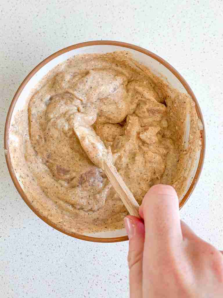 coating chicken in yogurt seasoned for chicken shawarma sheet pan dinner