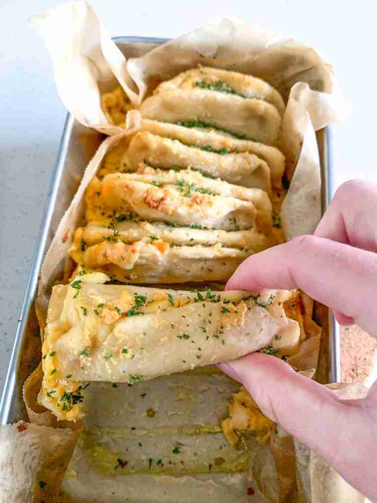freshly baked cheesy sourdough garlic pull apart bread being pulled apart