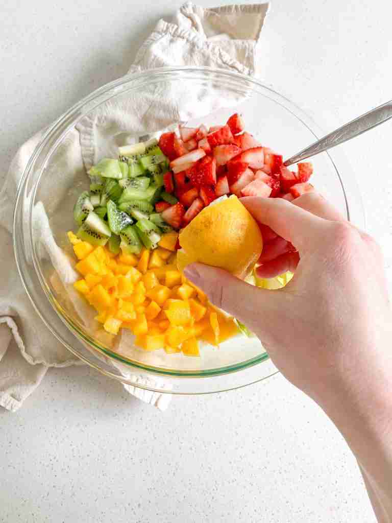 fruit in a bowl for spring fruit salad and lemon getting squeezed on top