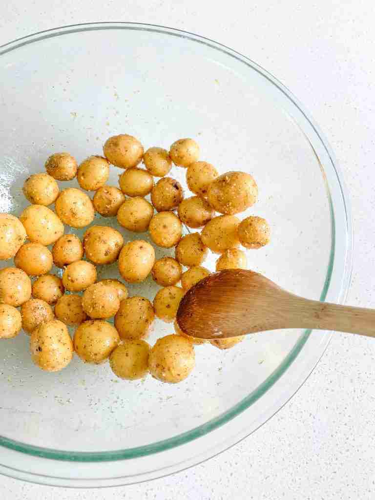 baby potatoes getting coated with seasoning and oil for lemon potatoes recipe