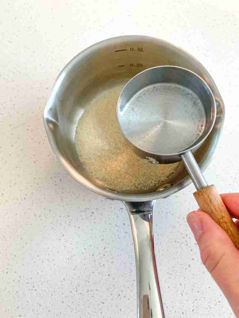 pouring water and cane sugar into a pan for mint julep punch