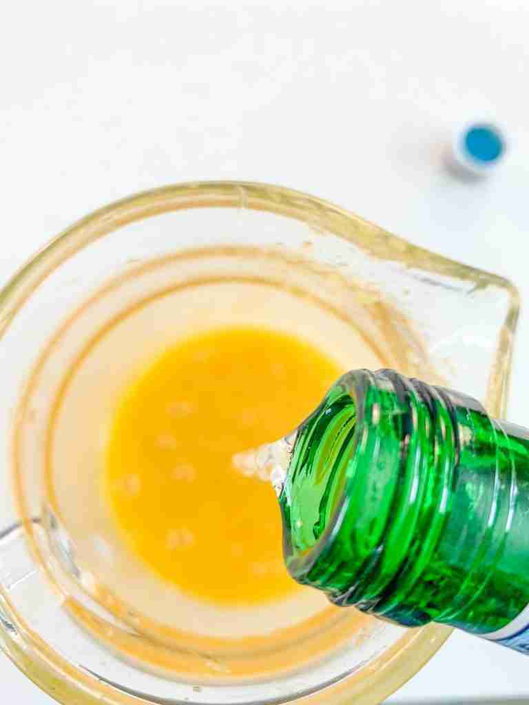 pouring sparkling water into the pitcher for mint julep punch