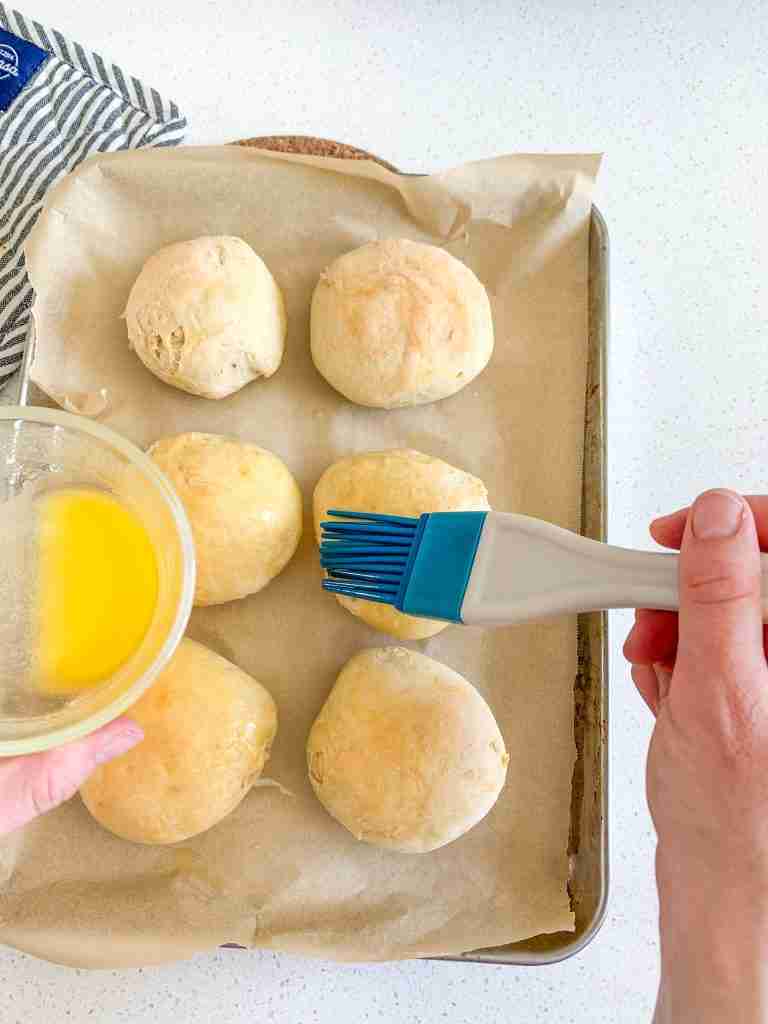 brushing butter on baked sourdough brioche buns
